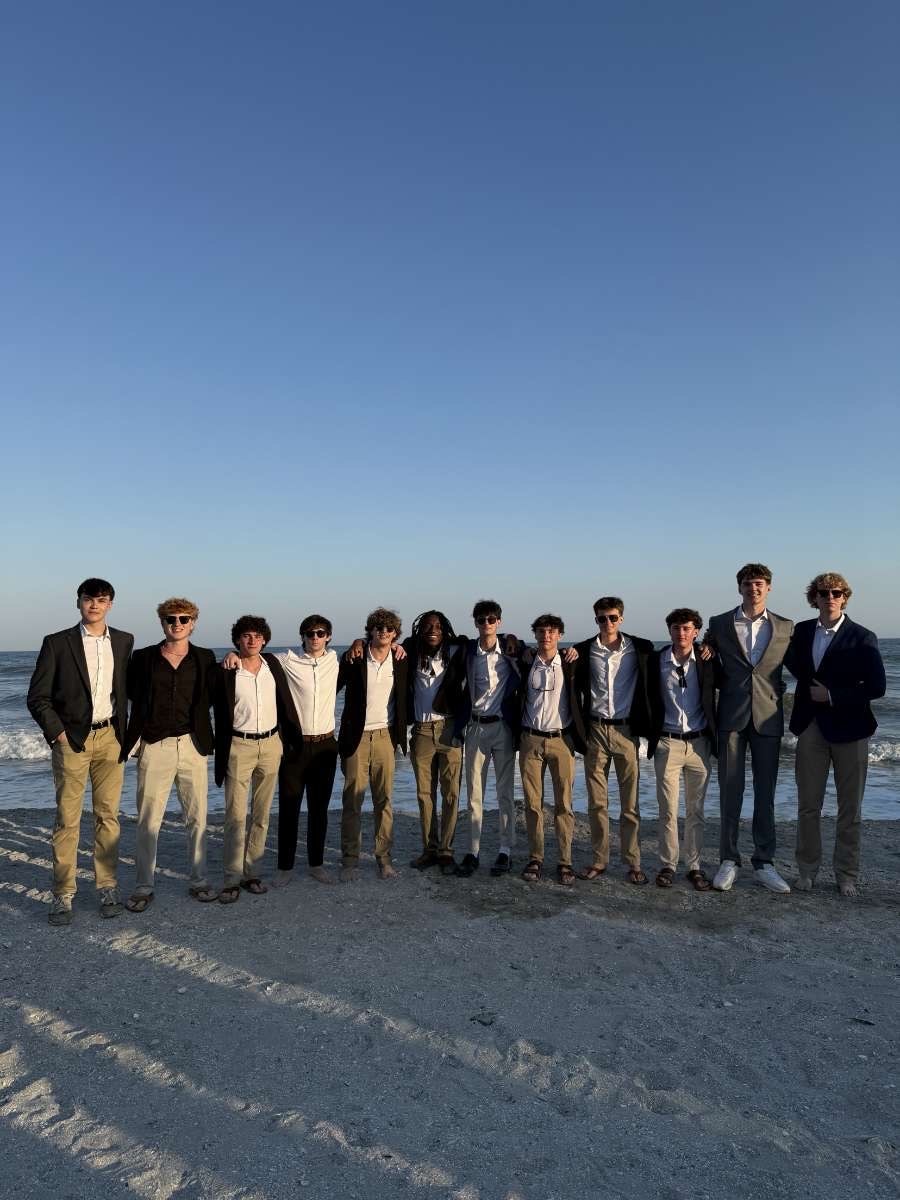 Brothers in navy blazers and khakis lined up along the shoreline