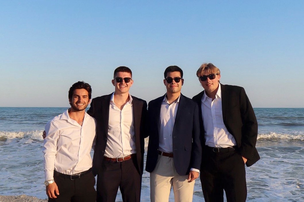 Four brothers in suits on the beach at sunset